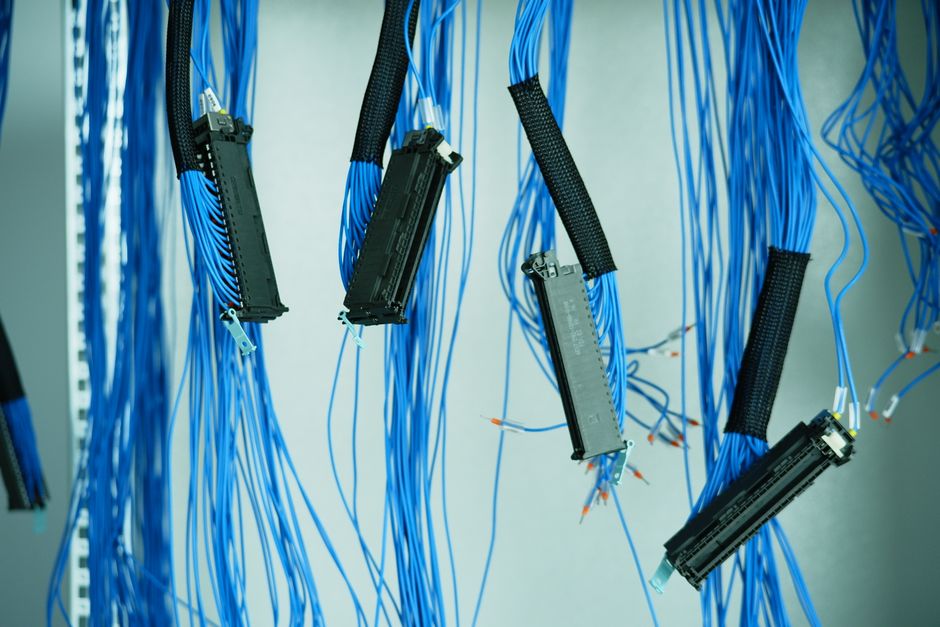 Primer plano de cables ethernet azules colgando en un centro de datos, destacando conexiones tecnológicas.