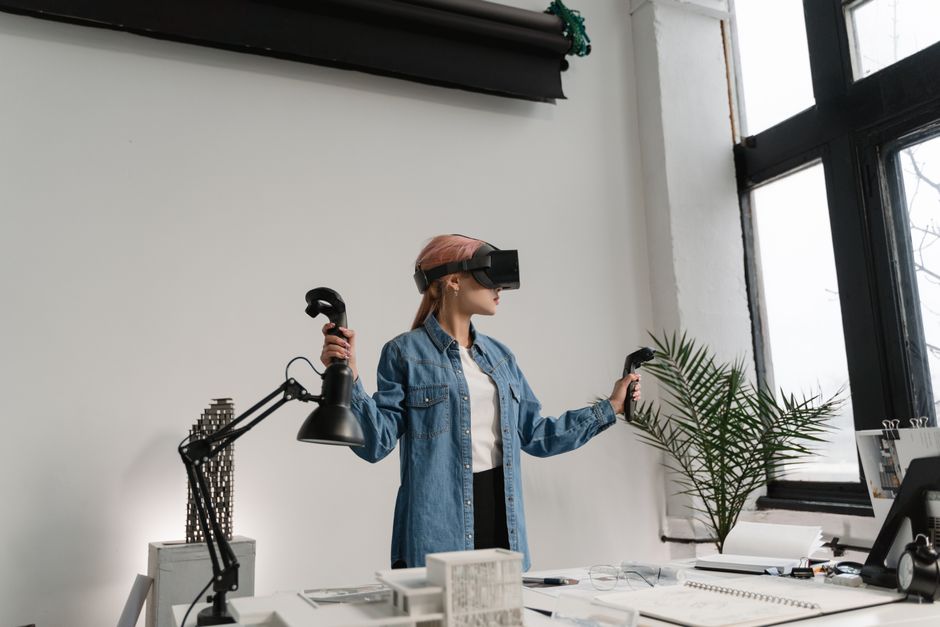 Mujer con auriculares VR y chaqueta de mezclilla explora un mundo virtual en una oficina contemporánea.
