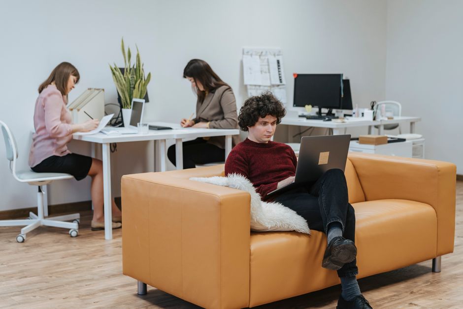 Personas colaborando en un espacio de oficina moderno con portátiles y documentos.