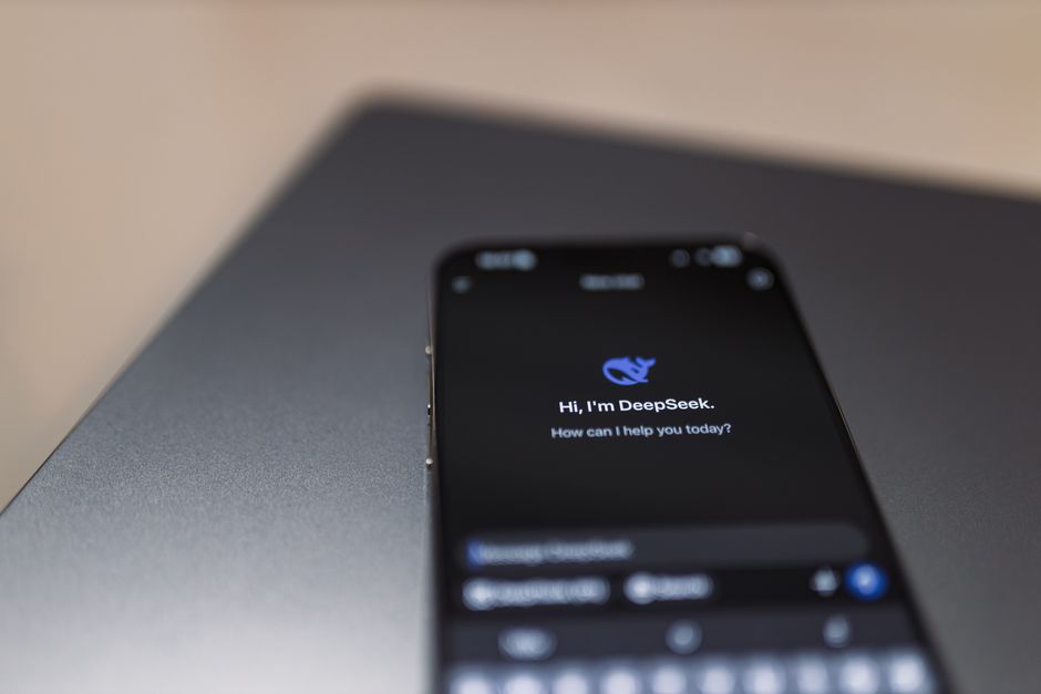 Primer plano de un teléfono inteligente con interfaz de asistente de inteligencia artificial en la pantalla sobre una computadora portátil.