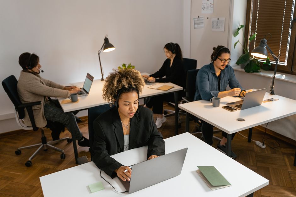 Equipo diverso de agentes de centro de llamadas trabajando en computadoras en un entorno de oficina, enfocados en tareas.