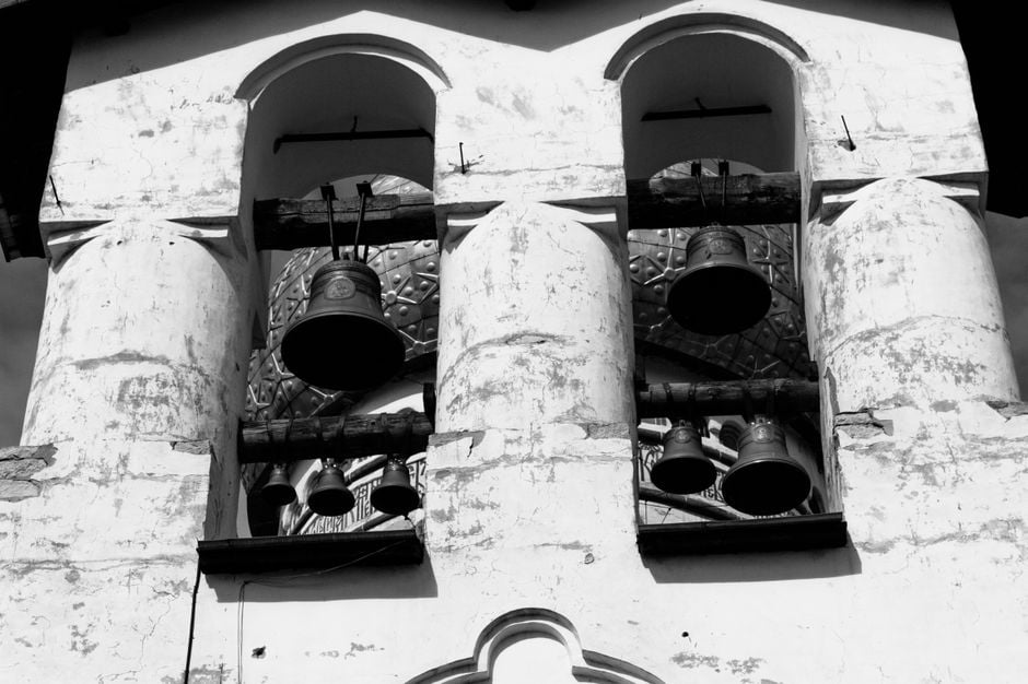 Imagen monocromática de un antiguo campanario con campanas antiguas.
