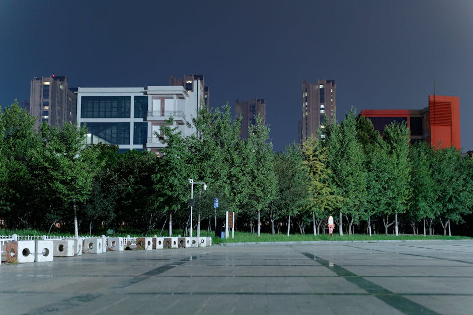 Una escena nocturna tranquila con edificios urbanos y exuberante vegetación bajo un cielo despejado.