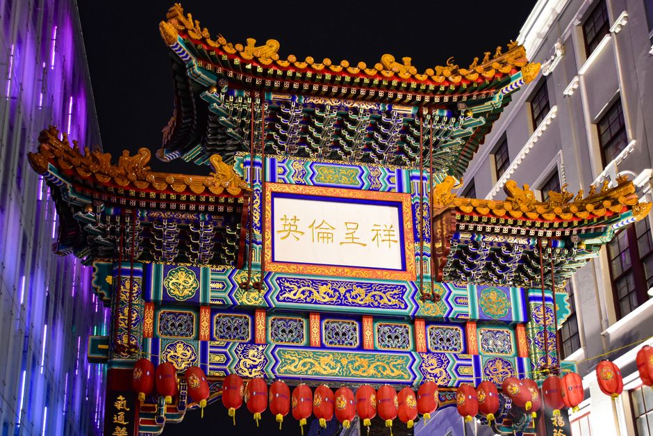 Vibrante puerta china en el Barrio Chino de Londres, iluminada por la noche, exhibiendo una arquitectura intrincada.