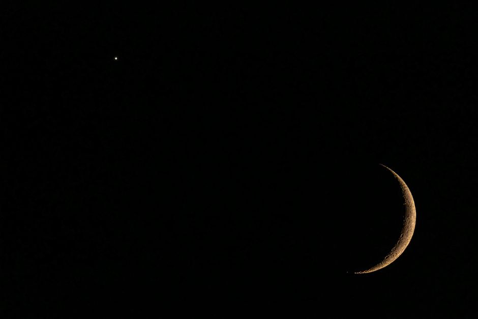 Una vista impresionante de una luna creciente y una estrella contra un cielo nocturno oscuro, que captura la belleza celestial.