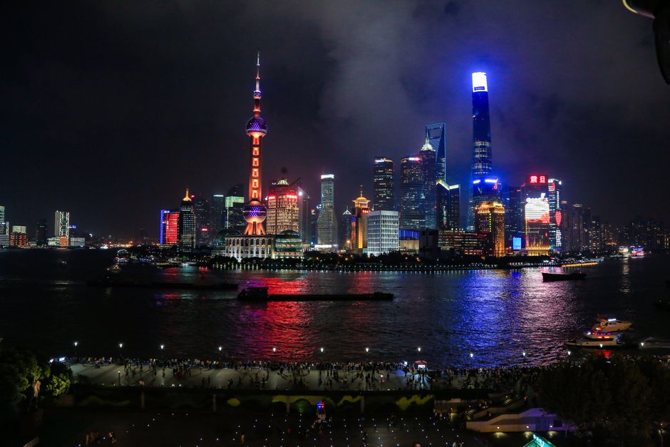 Horizonte iluminado de Shanghái con reflejos en el río Huangpu por la noche.