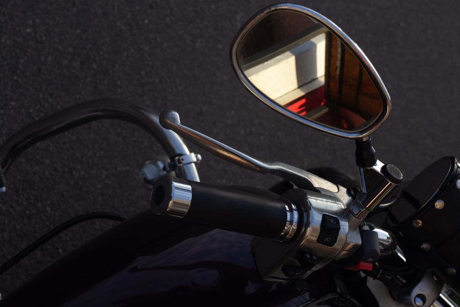 Imagen detallada del manillar de una motocicleta con espejo mostrando el reflejo.