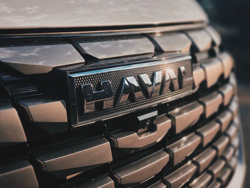 Vista detallada de la parrilla de un automóvil Haval, que muestra su diseño moderno y la imagen de marca bajo luz natural.