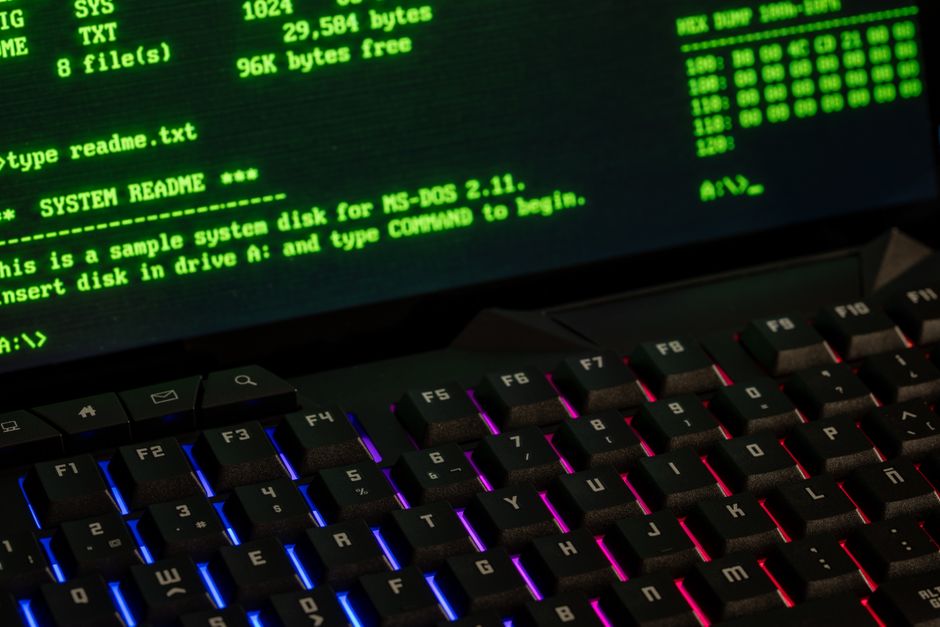 Acercamiento a una pantalla de computadora retro mostrando comandos MS-DOS con un teclado vibrante.