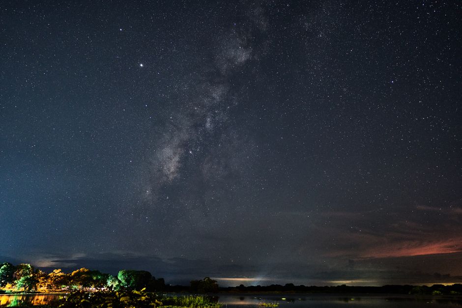 Una vista impresionante de un cielo estrellado despejado sobre un lago tranquilo, capturando la serenidad de la naturaleza por la noche.