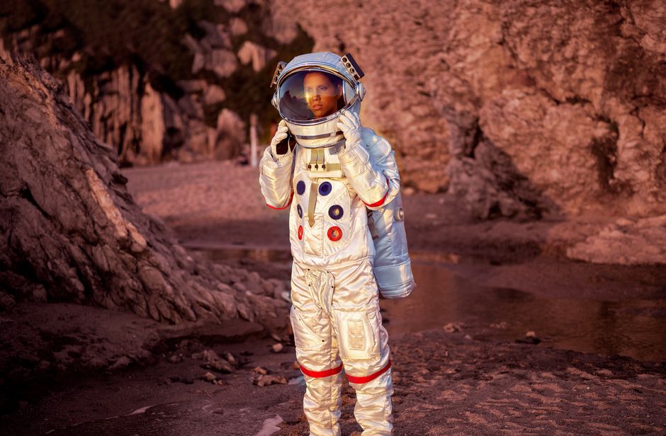Astronauta en un traje espacial explora un entorno desértico rocoso al atardecer.