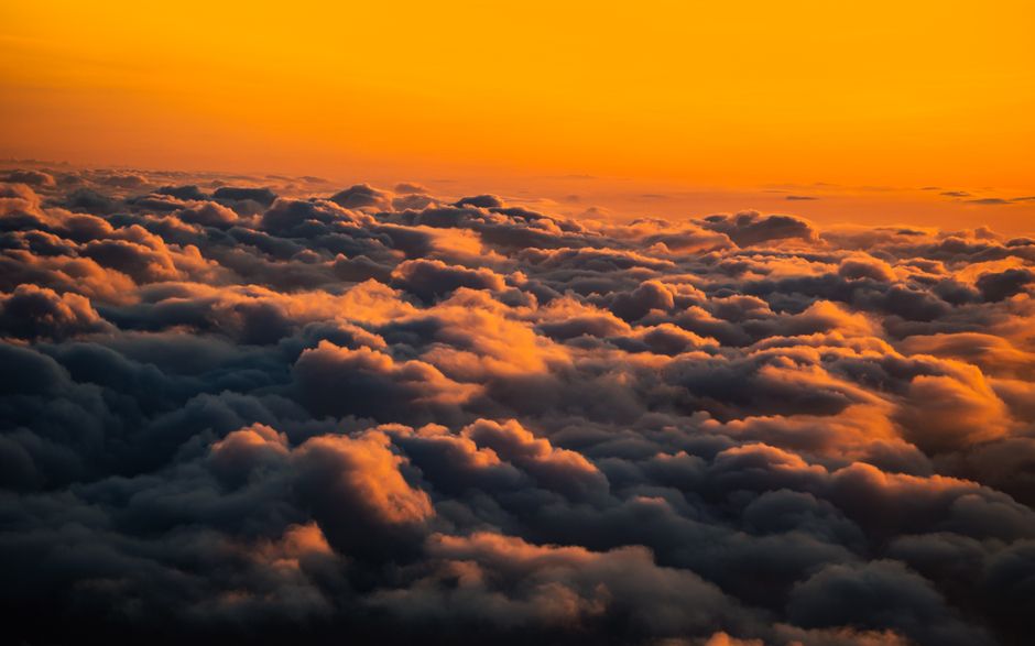 Una impresionante vista aérea de nubes iluminadas por un vívido cielo de atardecer.