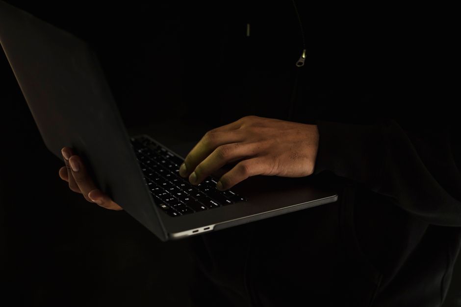 Silueta de una persona usando un portátil en un entorno oscuro, enfatizando el trabajo en línea o la seguridad.