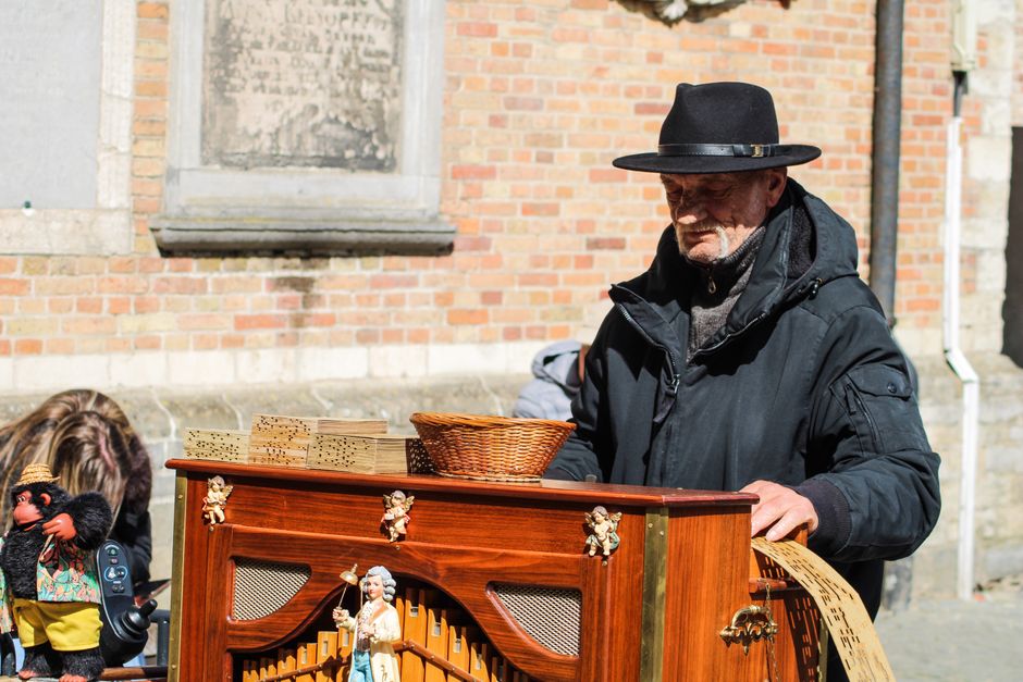 Un artista callejero tocando un organillo en Brujas, Bélgica, recreando una escena europea clásica.