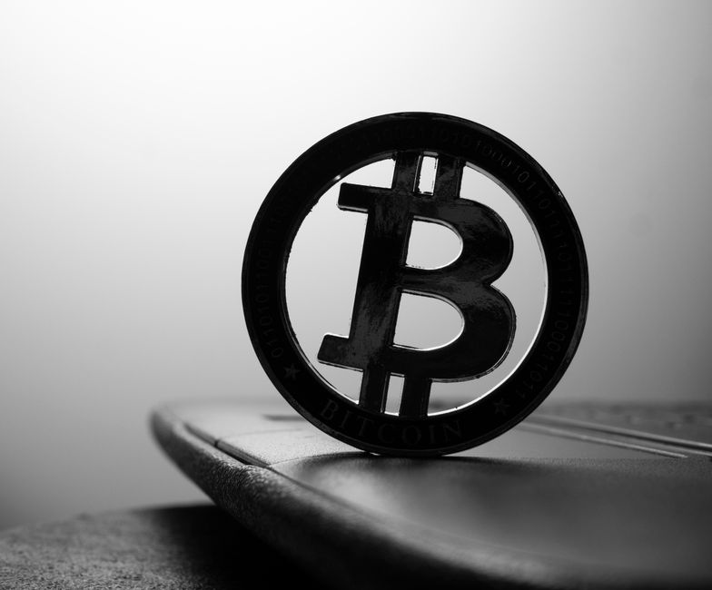 Una imagen en blanco y negro en primer plano de un símbolo de Bitcoin sobre un portátil.