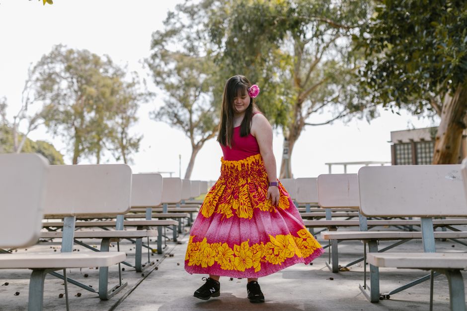 Niña joven vistiendo un vestido colorido con estampados florales en un parque al aire libre, disfrutando de un momento despreocupado.