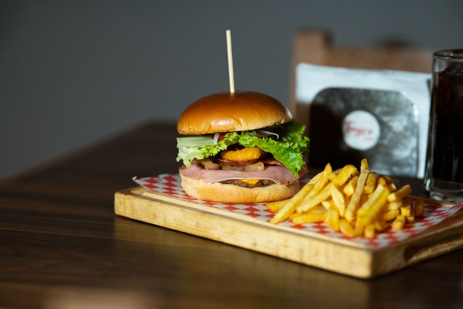 Deliciosa hamburguesa con lechuga fresca y patatas fritas en una tabla de madera, ideal para menús de comida.