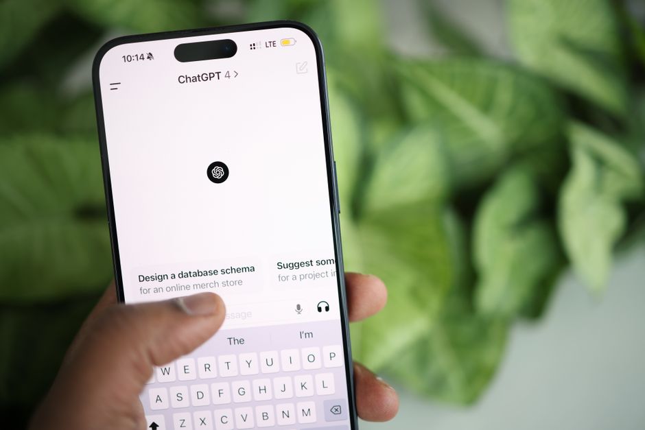 Mano sosteniendo smartphone que muestra la interfaz de ChatGPT, rodeada de vegetación.