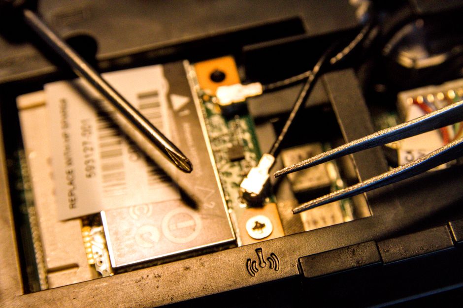 Vista detallada de las partes internas de una computadora portátil que se están reparando con herramientas.