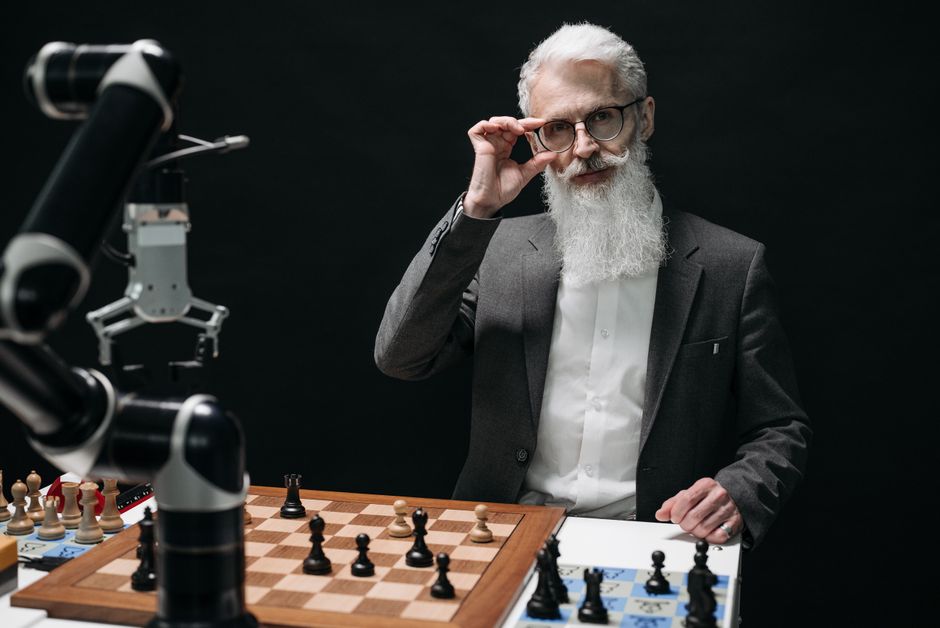 Hombre mayor strategizando en un juego de ajedrez contra un robot, mostrando IA en actividades de ocio.