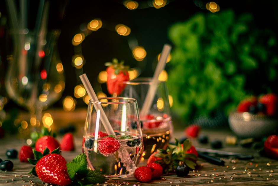 Cócteles refrescantes con fresas y frutos rojos en un ambiente festivo, ideal para reuniones navideñas.