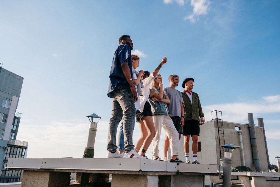 Un grupo diverso de amigos disfrutando de un día soleado en una azotea, abrazando la vida urbana y la amistad.