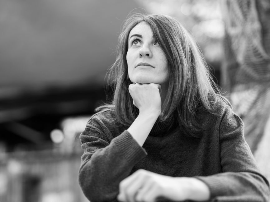 Retrato en blanco y negro de una mujer mirando pensativa al aire libre. Emocional y serena.