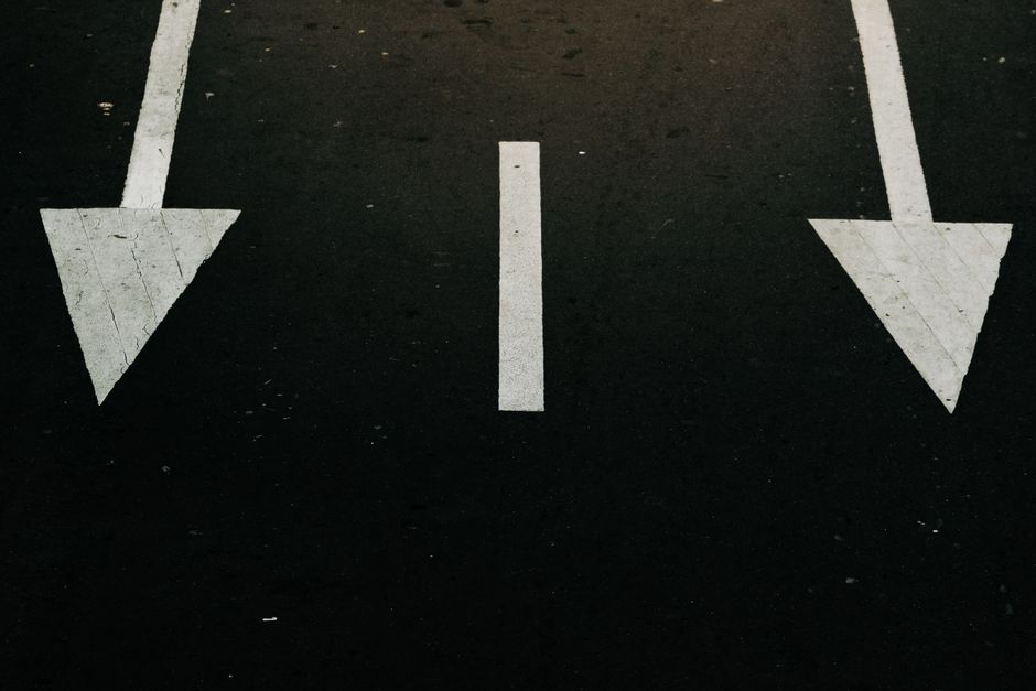 Flechas de dirección del tráfico en una calle de la ciudad, simbolizando decisión y navegación.