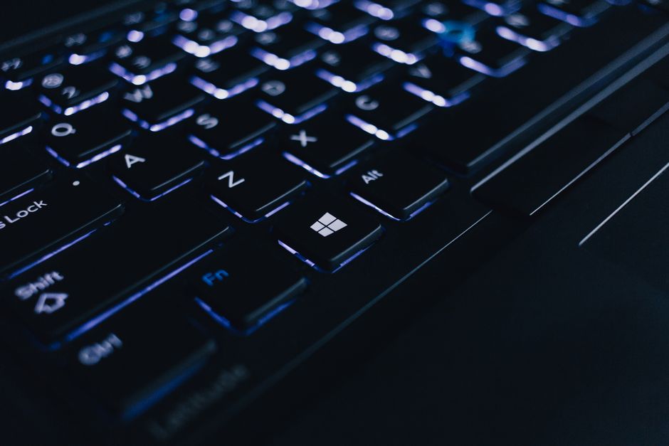 Vista detallada de un teclado de portátil iluminado que muestra teclas individuales y efecto de retroiluminación.