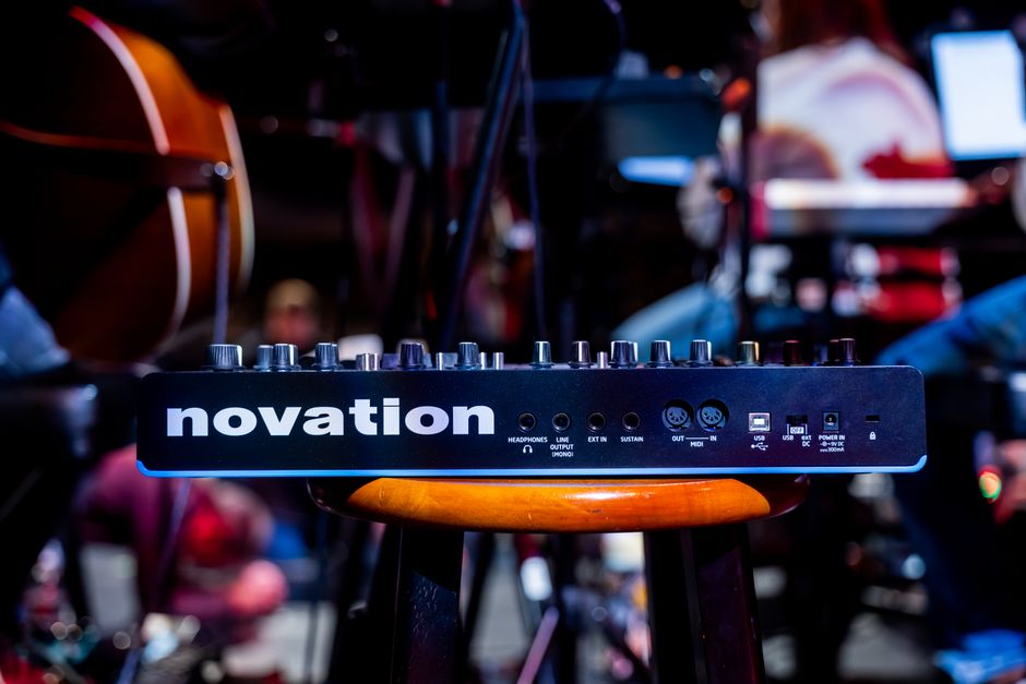 Dispositivo de audio Novation en un banco durante la configuración de un concierto en vivo, mostrando tecnología musical.
