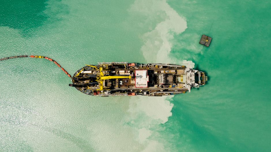 Toma aérea de un barco navegando por aguas turquesa vívidas, creando un contraste impactante.