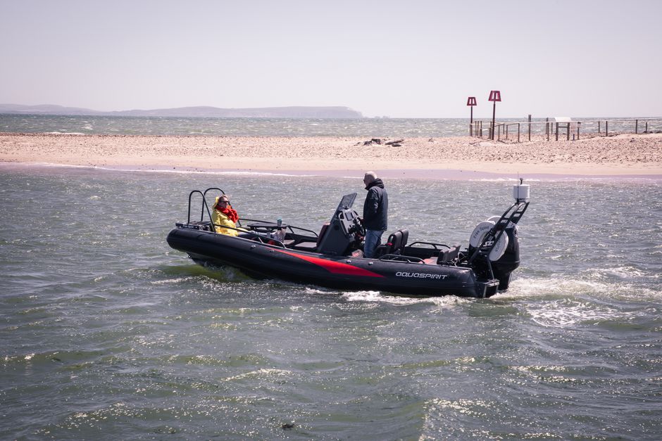 Una embarcación RIB con dos pasajeros navegando por la costa de Inglaterra en un día soleado.