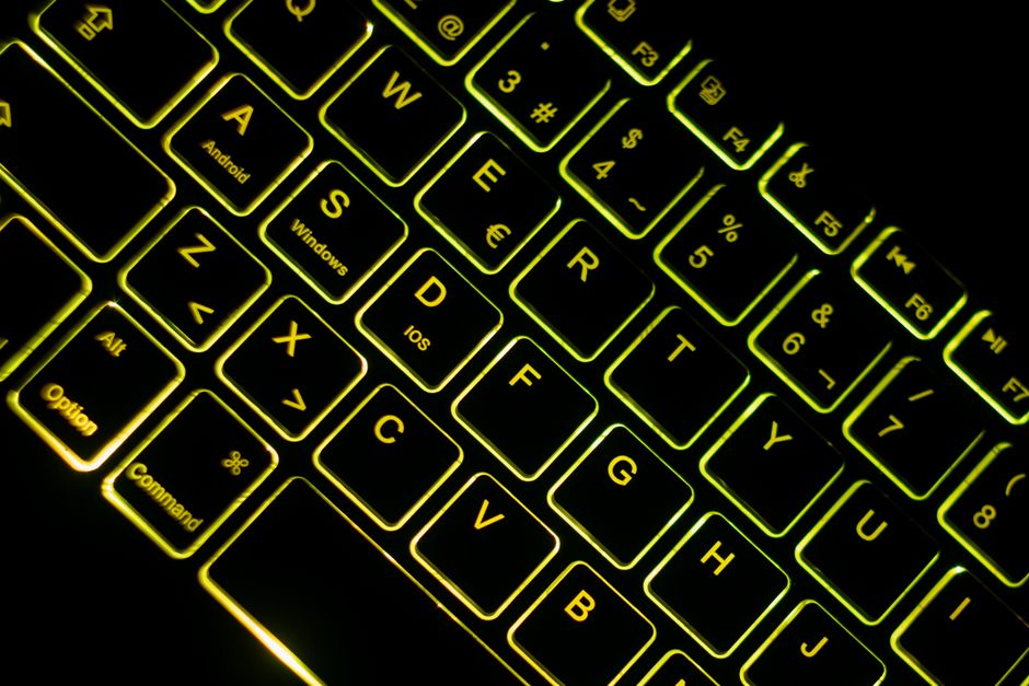 Primer plano de un teclado retroiluminado con neón en un entorno oscuro, con un vívido brillo verde-amarillo.