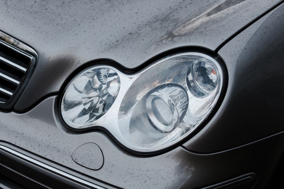Vista detallada del faro y la rejilla de un coche que muestra un diseño automotriz moderno.