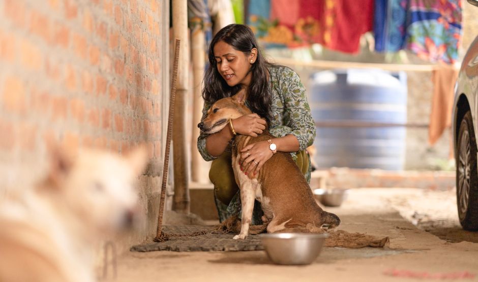 Una mujer abraza cariñosamente a su perro al aire libre, destacando la compañía.