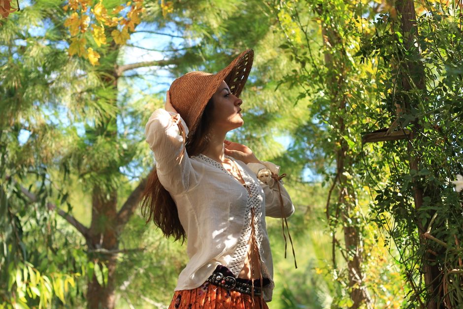 Una joven con un sombrero de paja disfruta de un día soleado en un bosque verde y frondoso.