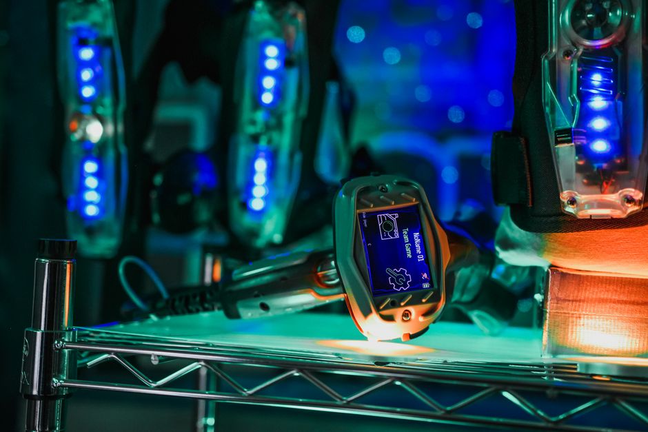 Vista en primer plano de equipo avanzado de laser tag con detalles iluminados en un entorno interior.