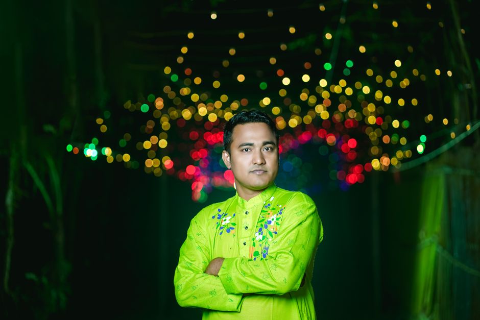 Retrato de un hombre con un atuendo tradicional brillante y luces bokeh de fondo.