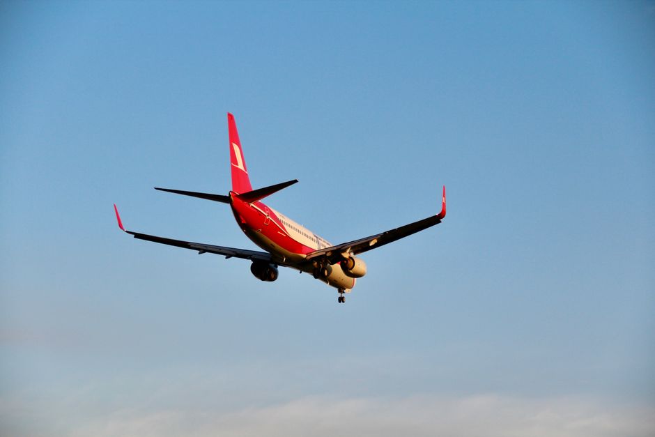 Un avión rojo volando contra un cielo azul claro durante el día.