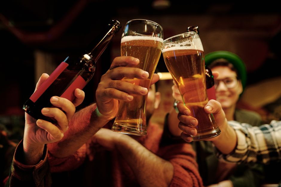 Grupo alegre de amigos brindando con vasos de cerveza en un ambiente animado de pub.