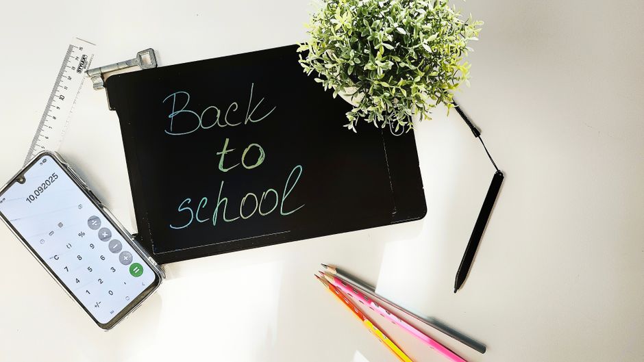 Vista superior de un espacio de trabajo con temática de regreso a clases con papelería y plantas.