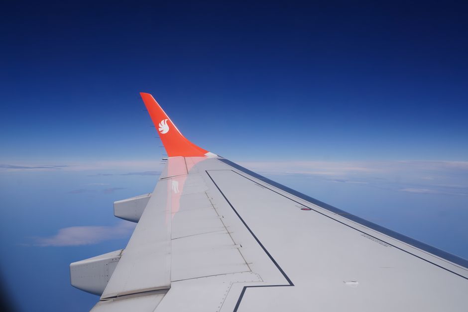 Una impactante imagen del ala de un avión en pleno vuelo contra un cielo azul intenso, que resalta los viajes y la aviación.