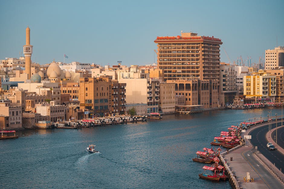 Una hermosa vista del Dubai Creek que muestra edificios tradicionales y barcos abra bajo la cálida luz del día.