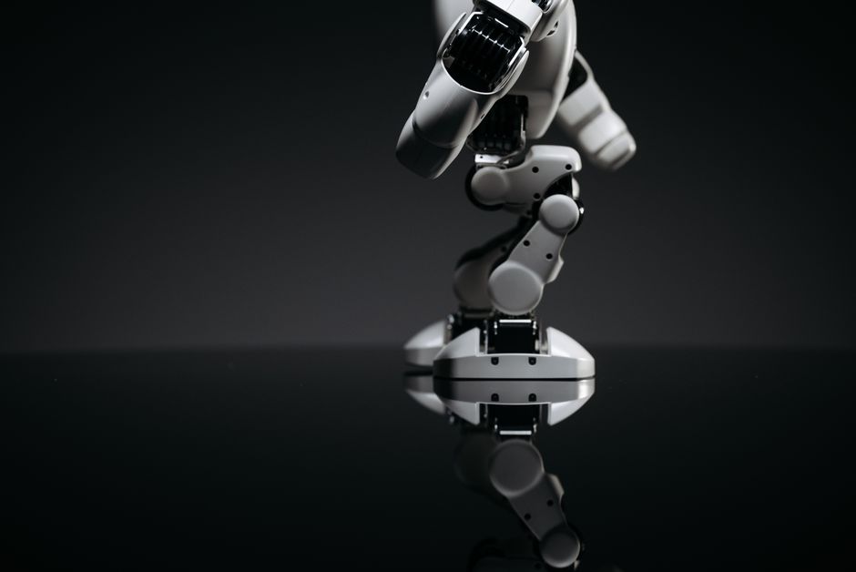 Una imagen en primer plano de un brazo robótico mecánico reflejándose en una superficie oscura, capturando la innovación industrial.