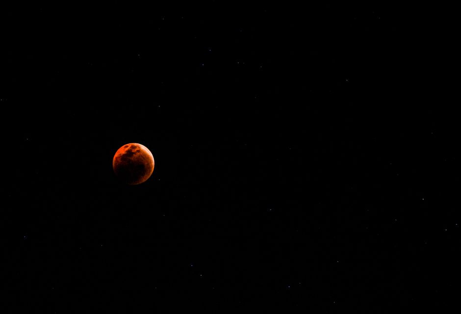Una vista cautivadora de una luna de sangre rodeada por un cielo nocturno lleno de estrellas.