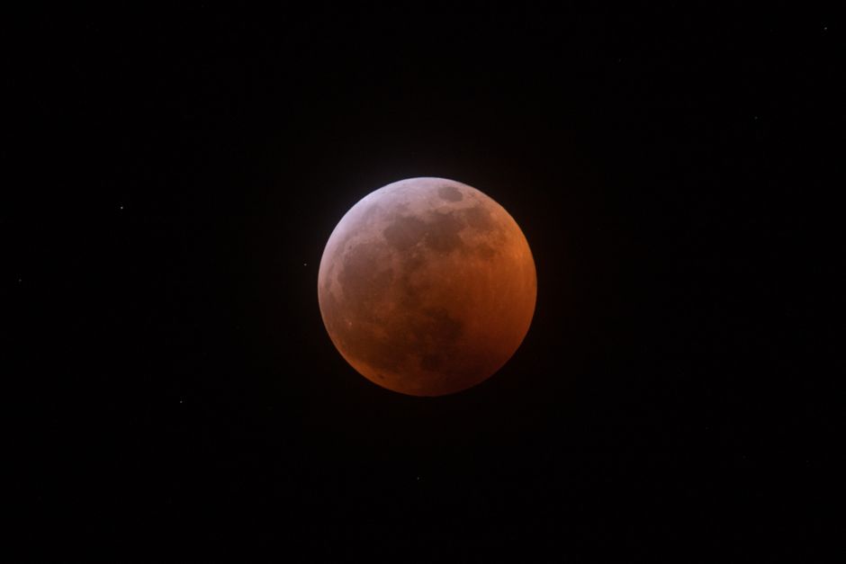 Impresionante imagen de una luna de sangre capturada durante un eclipse lunar contra un cielo estrellado.