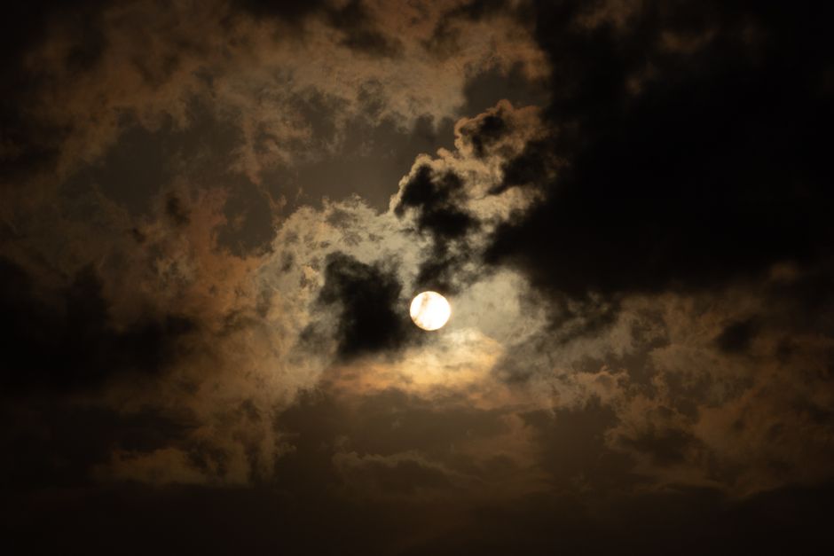 Una vista cautivadora de la luna llena brillando a través de dramáticas nubes, creando una atmósfera mística nocturna.