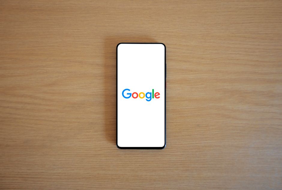 Un smartphone mostrando la página de inicio de Google sobre una superficie de madera, visto desde arriba.