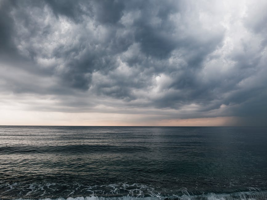 Una fotografía impresionante de nubes de tormenta oscuras que se reúnen sobre un océano en calma, creando un espectacular paisaje marino.