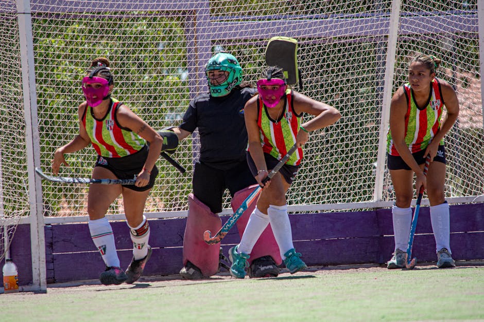 Jugadoras de hockey sobre césped con indumentaria colorida listas para la acción en el campo.